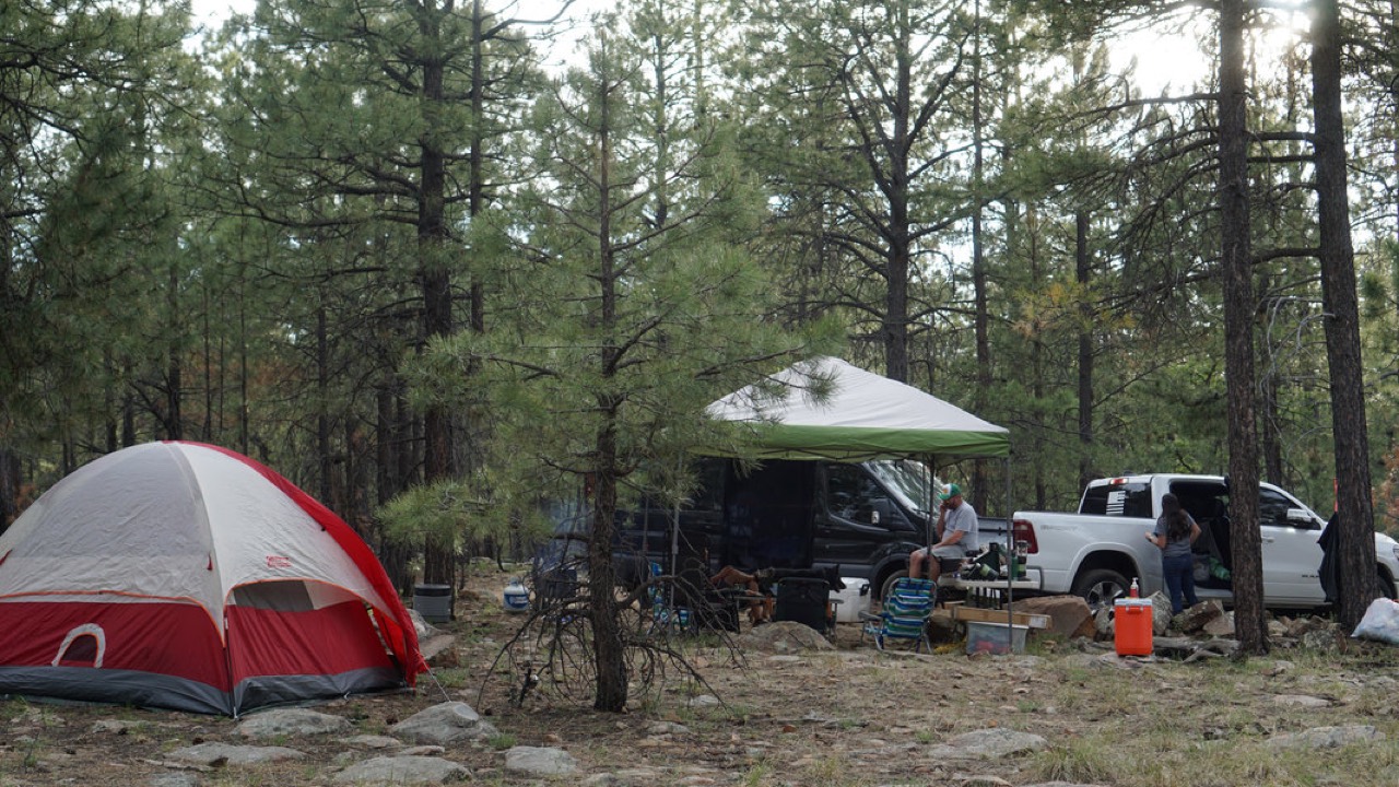 Tent on the left of a Woods Canyon campsite, with canopy and parked vehicles on the right