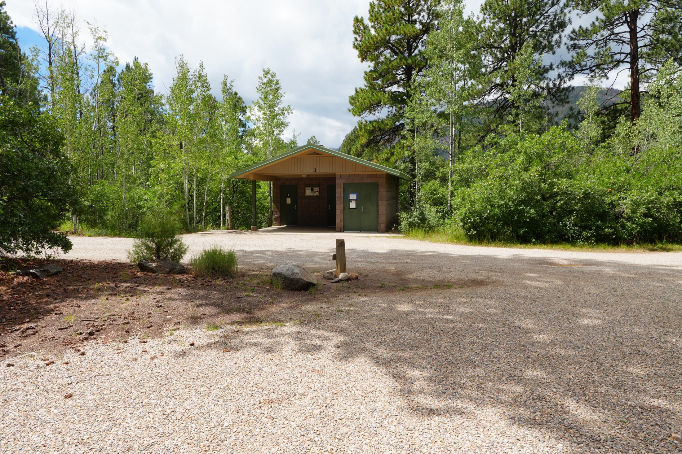 Campground vault toilet surrounded by green forest